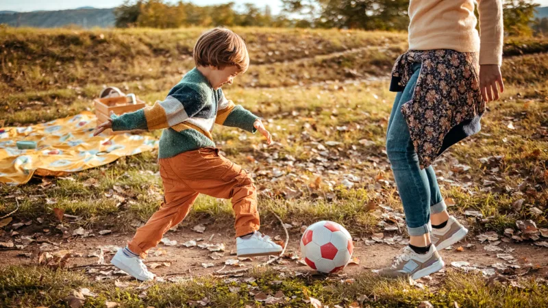 Eine Junge spielt mit einer Frau Fußball
