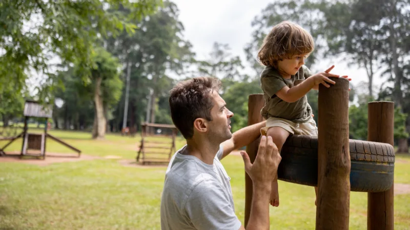 Kleines Kind mit Vater auf dem Spielplatz