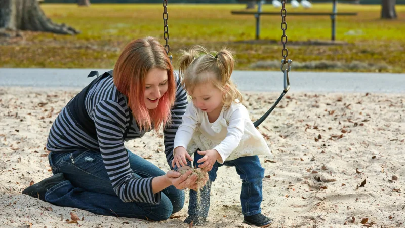 Mutter spielt mit ihrer Tochter im Sand
